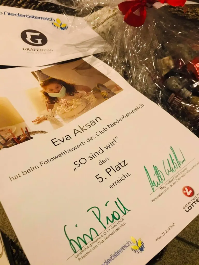 Urkunde: Eva Aksan erreichte beim Fotowettbewerb „SO sind wir!“ den 5. Platz, daneben Geschenkkorb