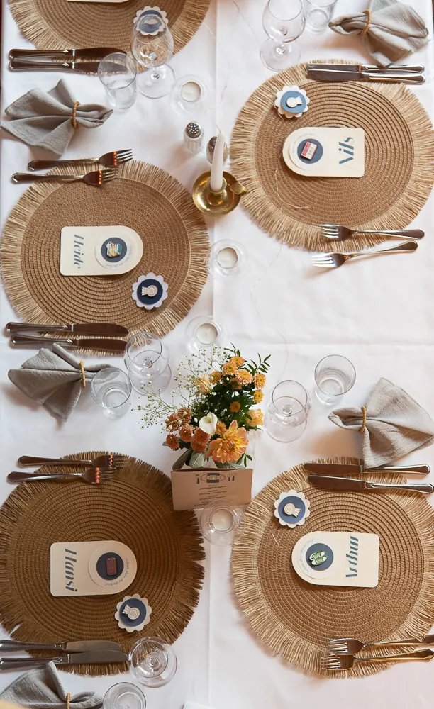 Festtafel von oben: runde Jute-Platzsets, Namenskärtchen, Kerzen und ein Sträußchen in Apricot.