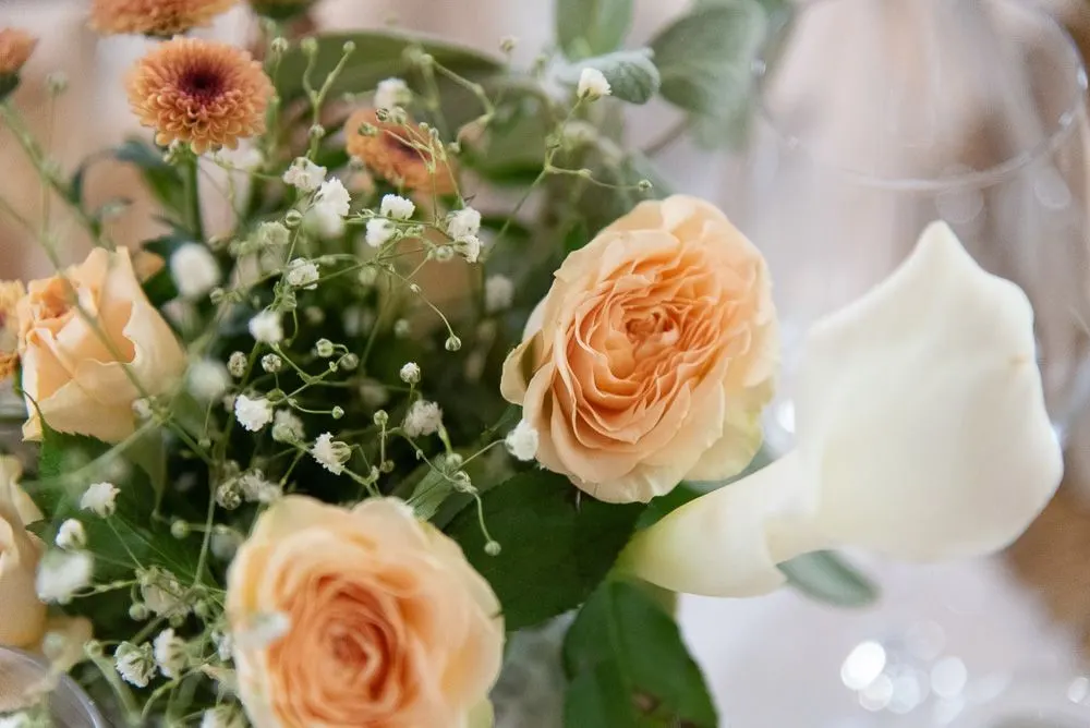 Tischschmuck aus apricotfarbenen Rosen und Schleierkraut