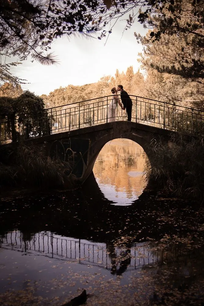 Silhouette des Paares auf einer Bogenbrücke, gespiegelt im Wasser