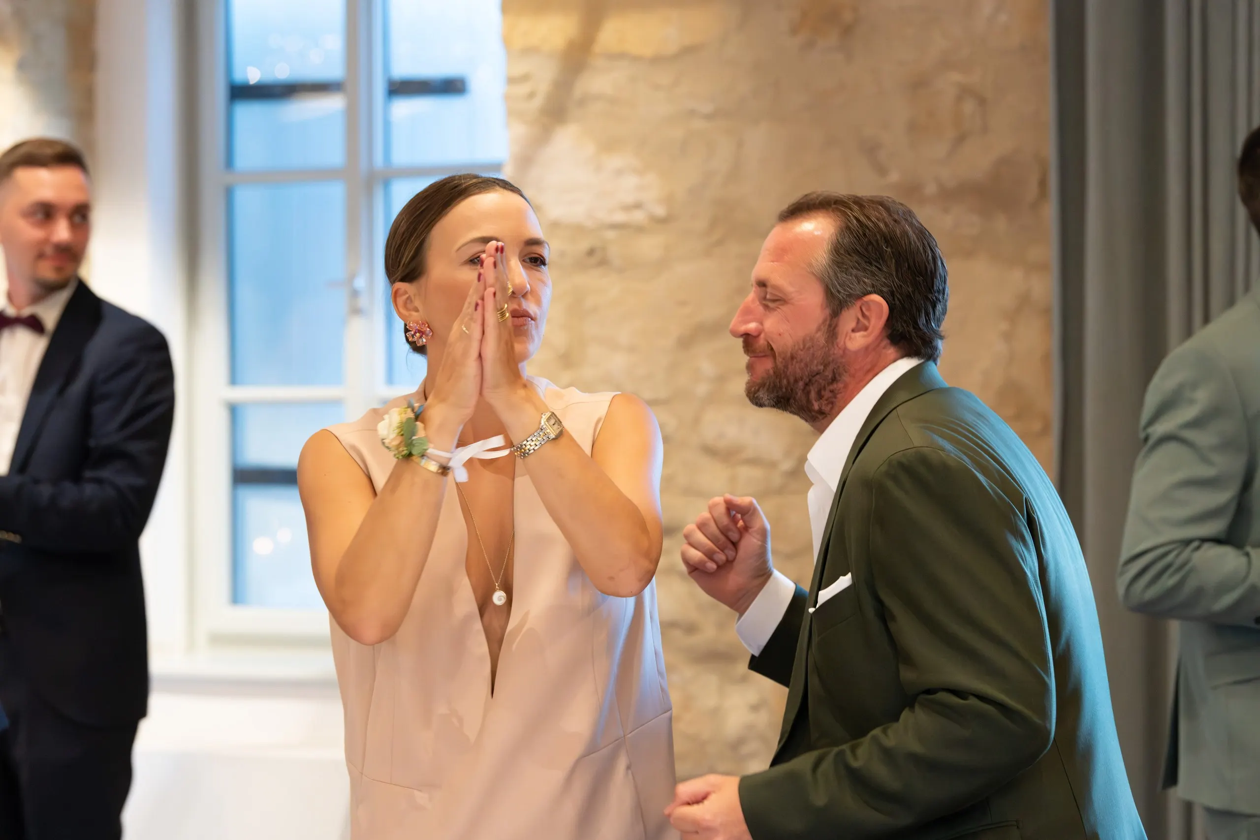 Ein Gast im grünen Sakko lacht einer gerührten Frau zu, die die Hände vor das Gesicht presst