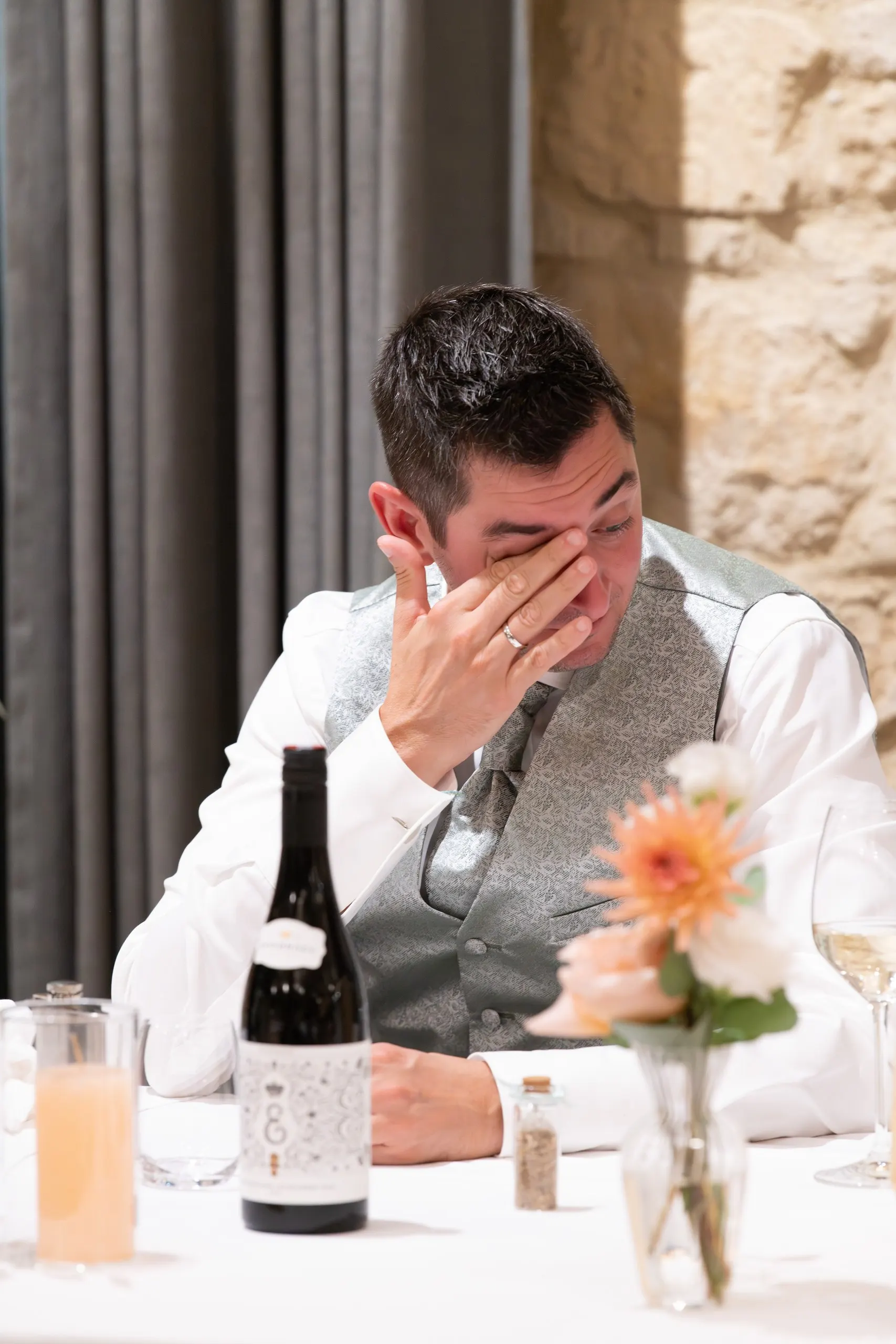 Martin sitzt am Tisch und wischt sich mit der Hand eine Träne aus dem Auge