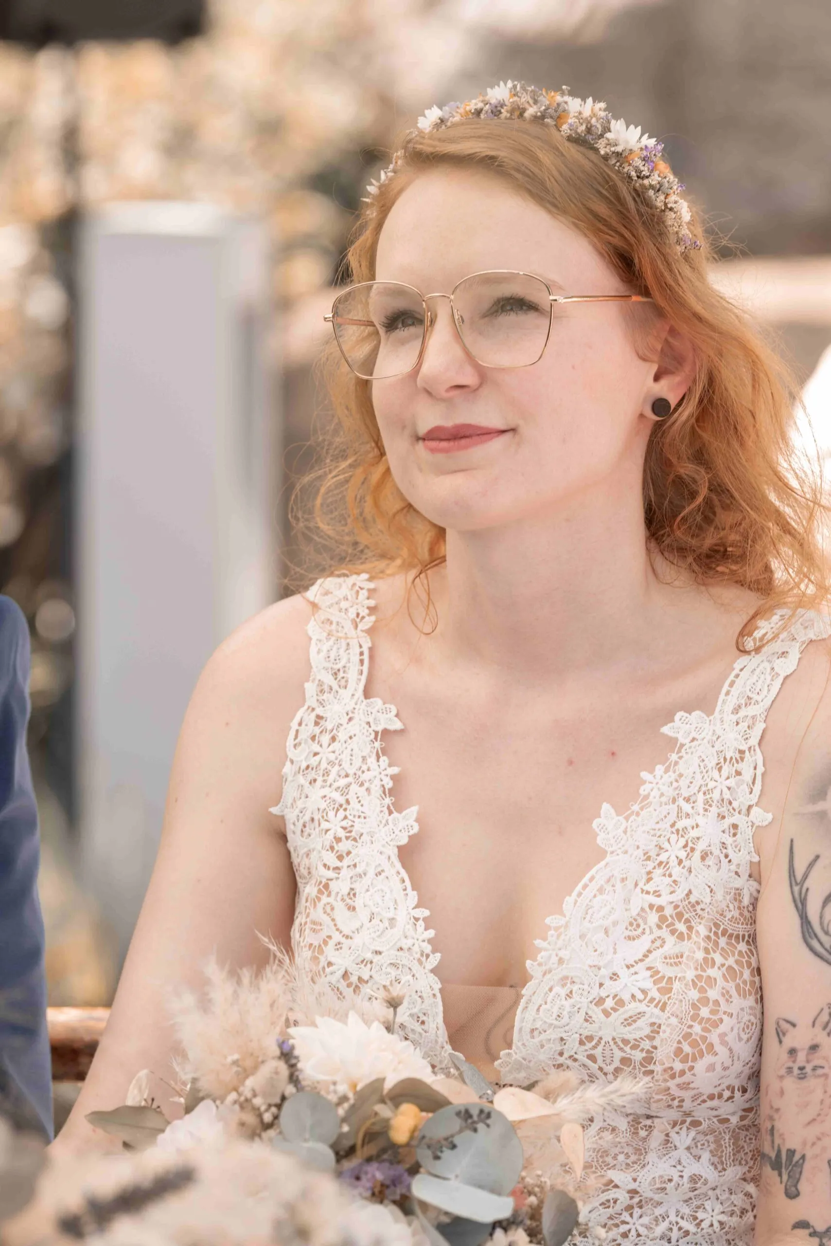 Chrisi mit Trockenblumenkranz und goldener Brille während der Trauung, den Strauß aus Trockenblumen im Arm.