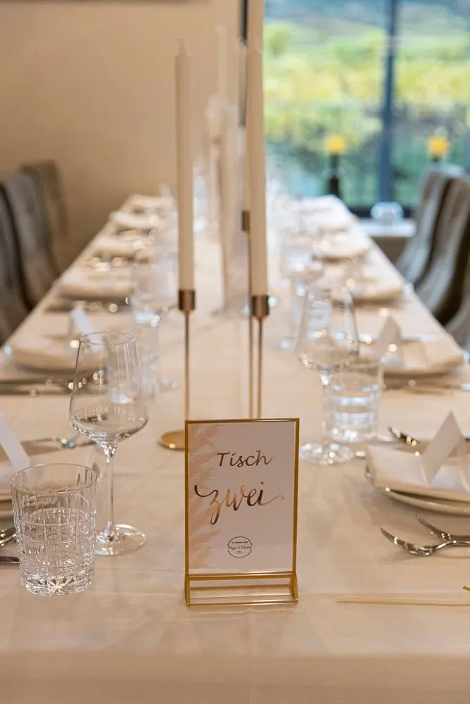 Festlich gedeckte lange Tafel mit Kerzen und Namenskarte