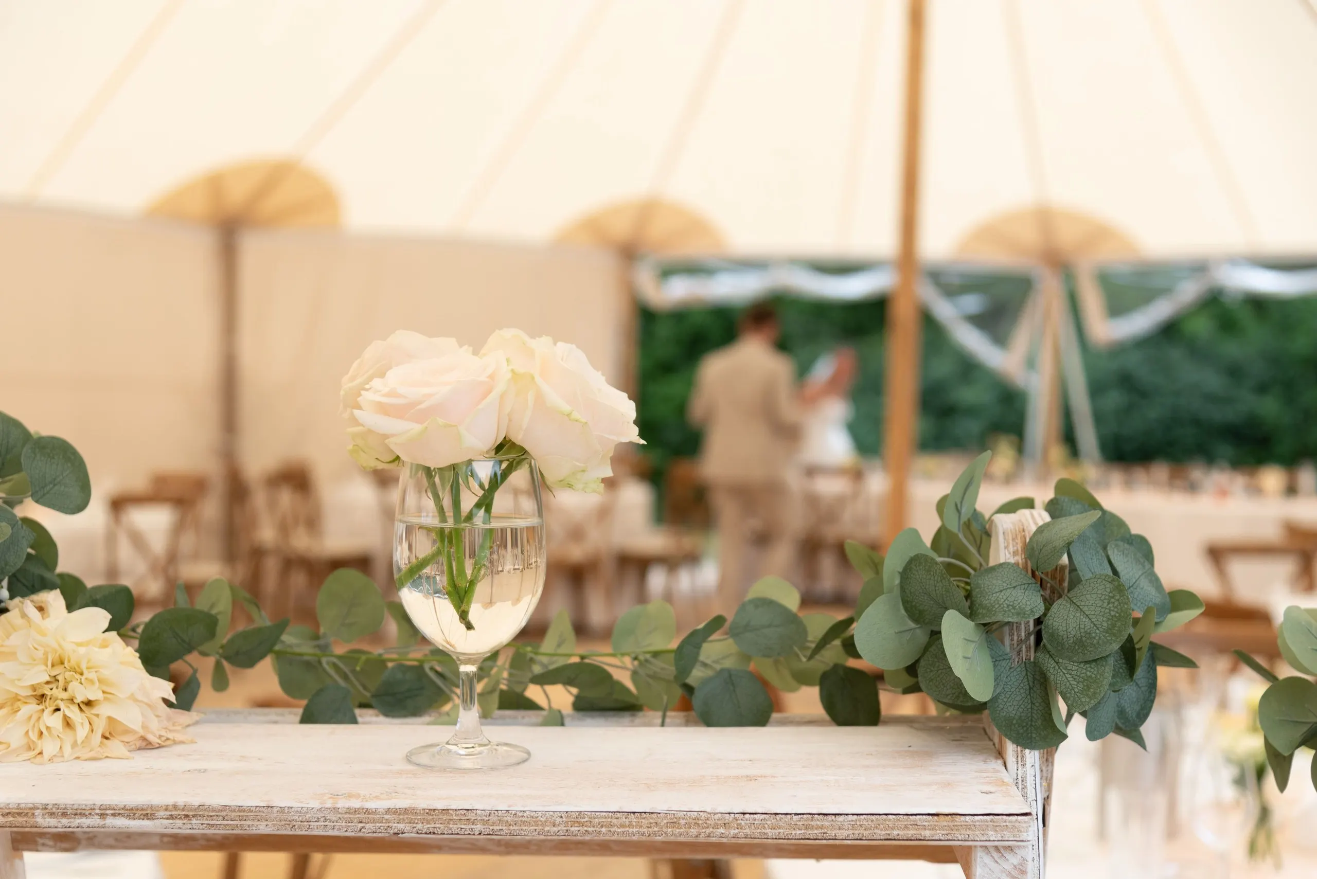 Weiße Rosen und Eukalyptus auf den Tischen im Festzelt