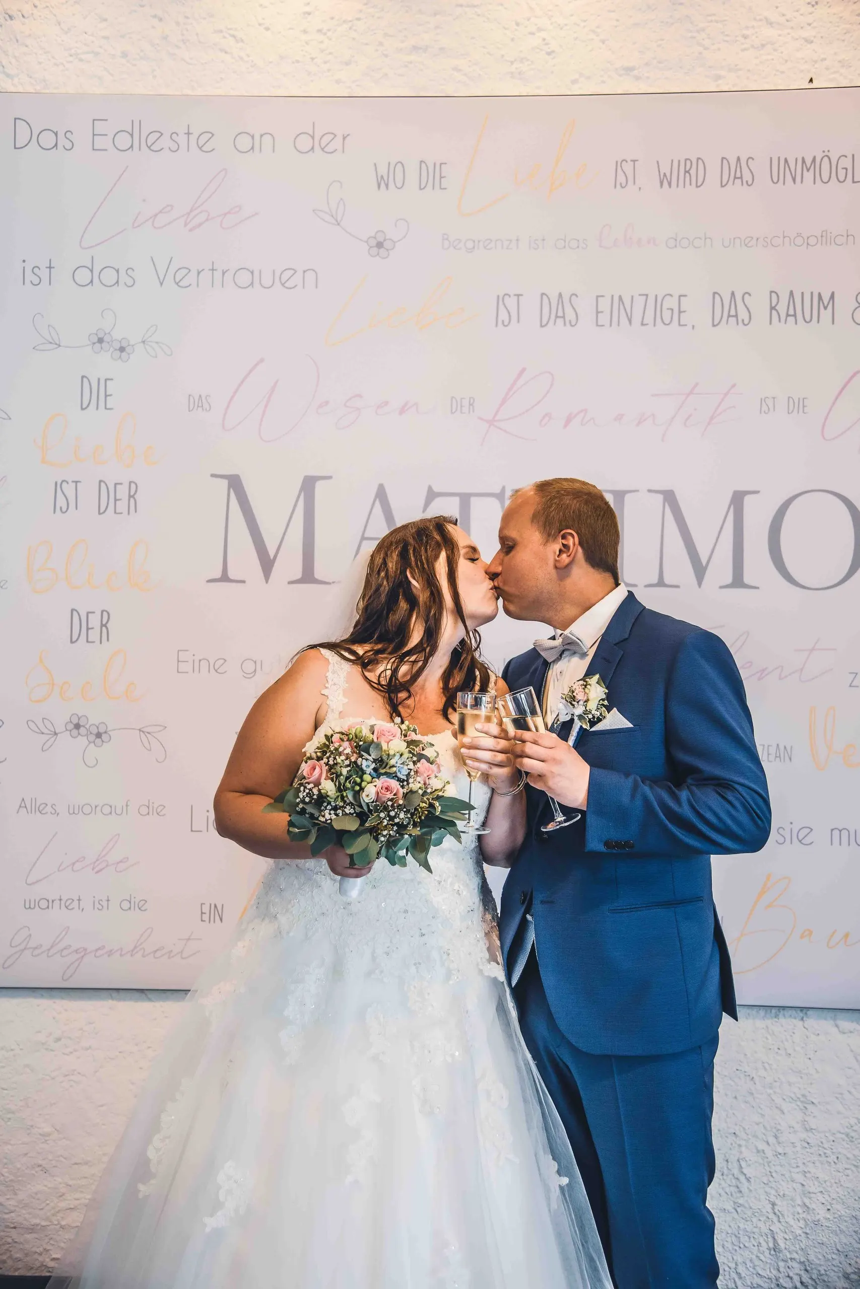 Kuss vor der Wand mit dem Matrimonium-Schriftzug