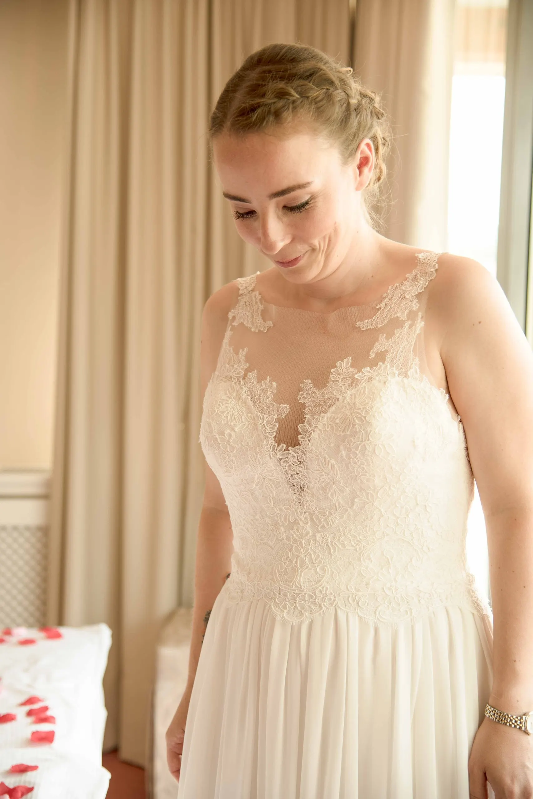 Die Braut im Spitzenkleid blickt lächelnd nach unten