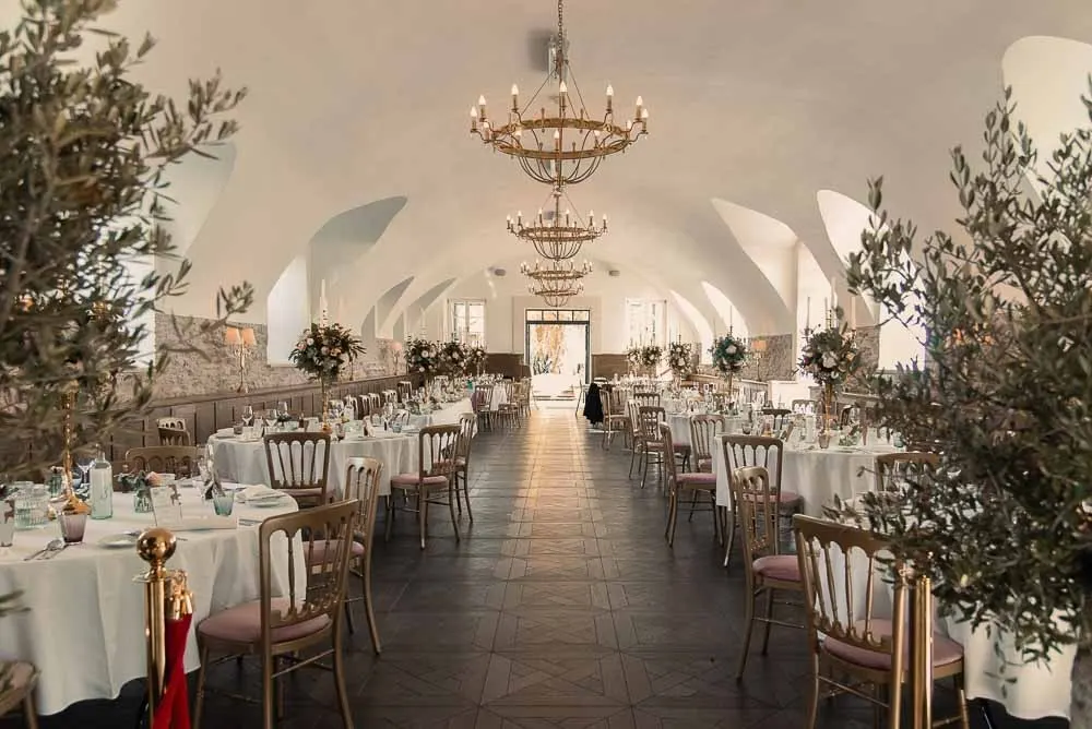 Festsaal unter dem Gewölbe mit Kristalllustern und runden Tafeln