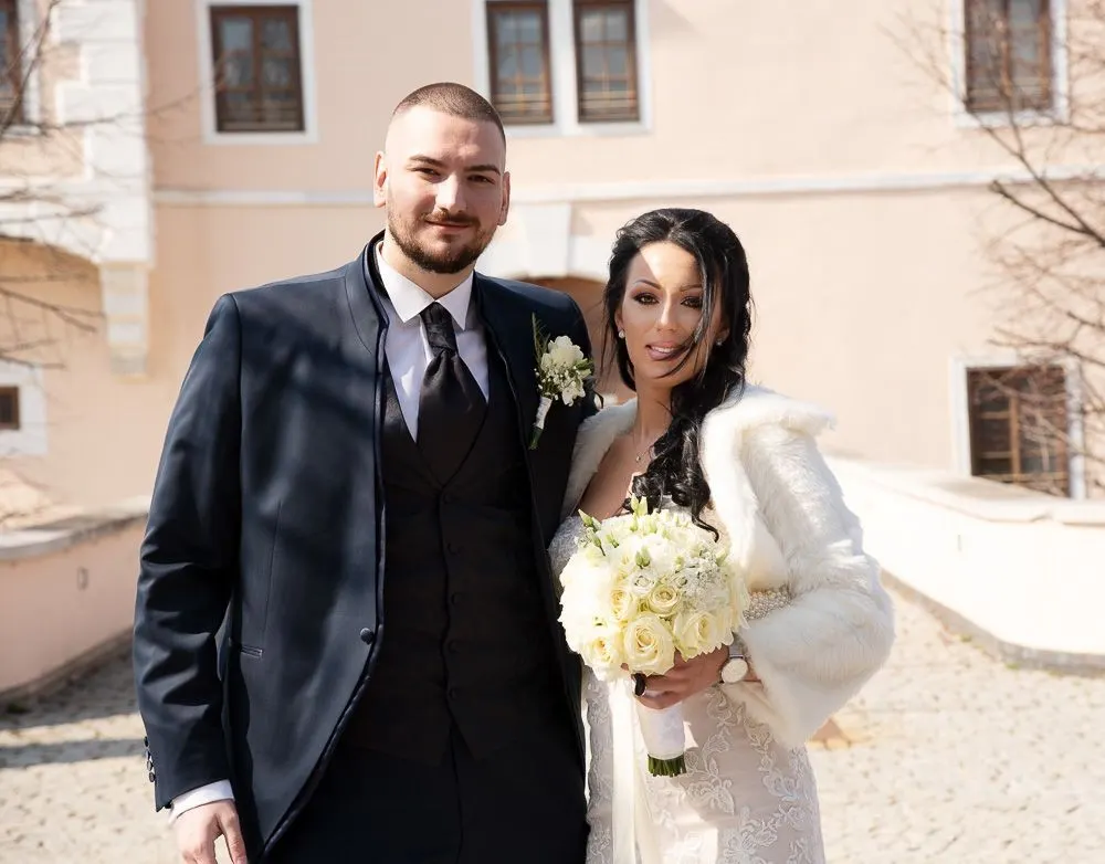 Das Brautpaar im Schlosshof von Schloss Vösendorf, sie mit weißem Rosenstrauß