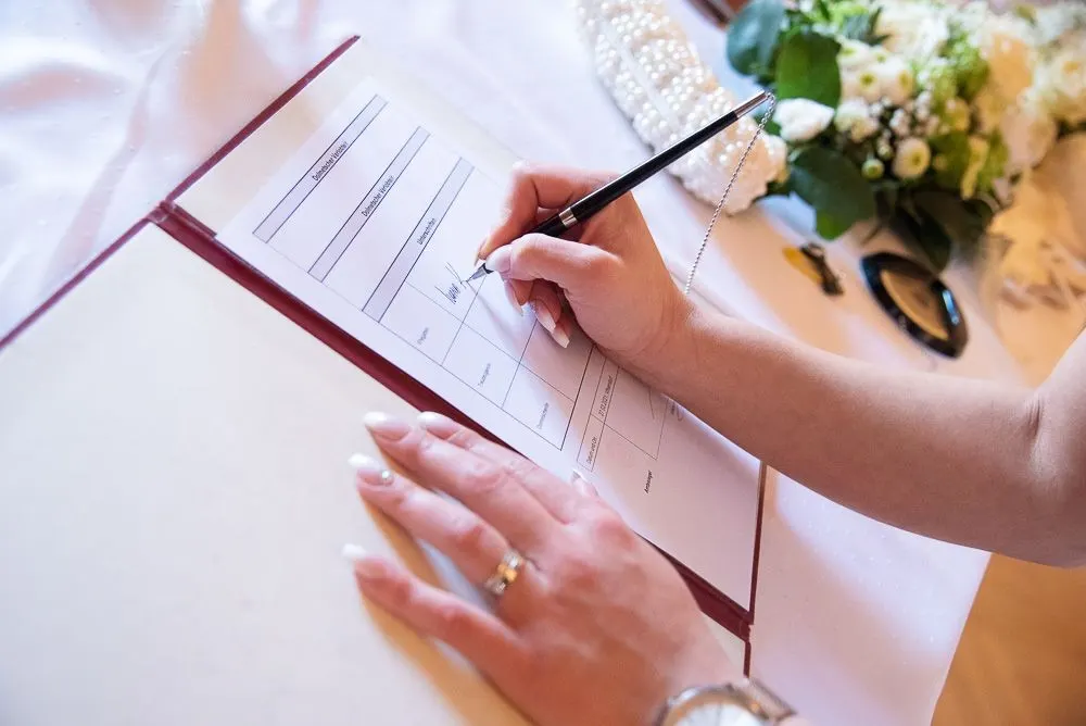 Die Braut unterschreibt die Heiratsurkunde