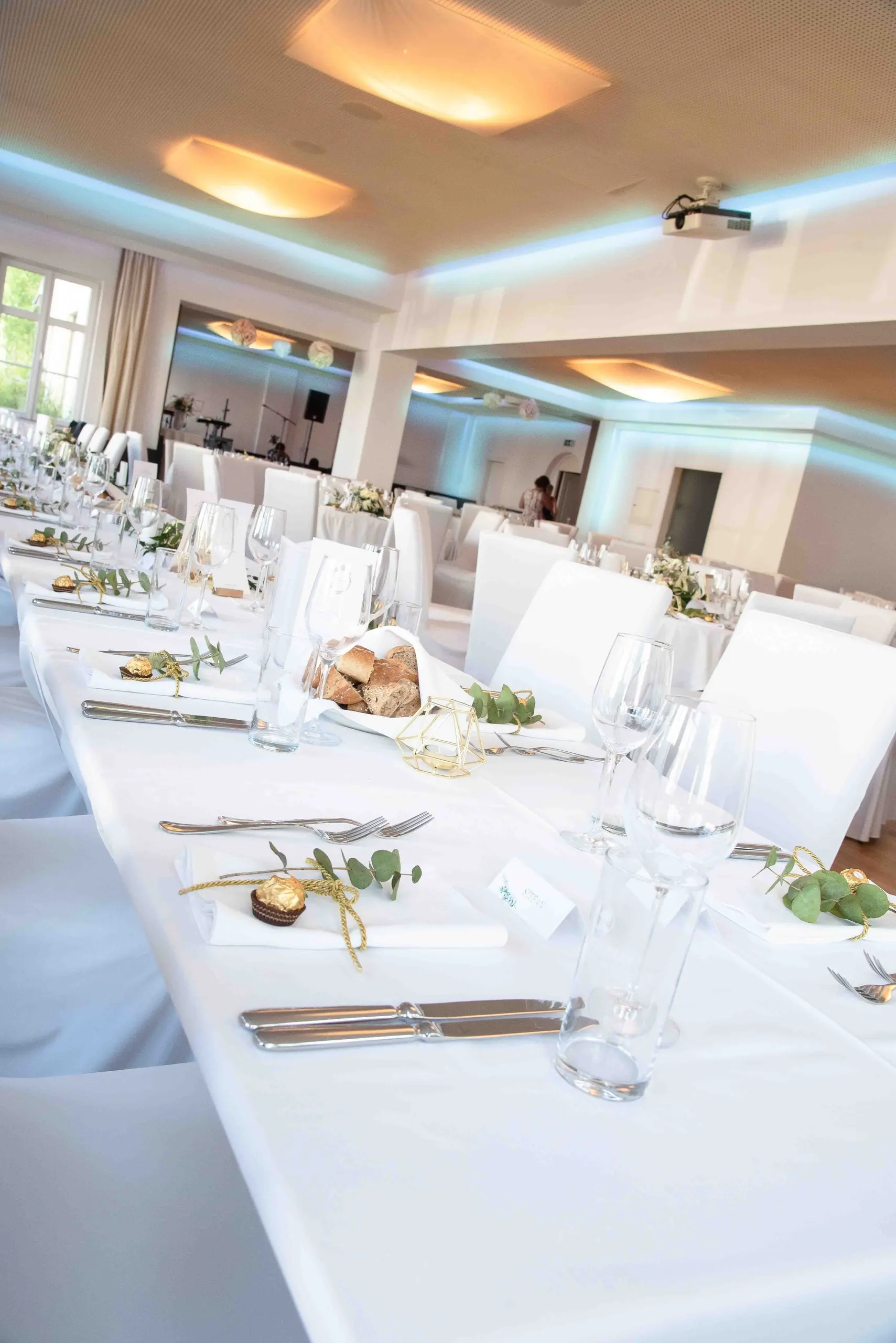 Lange weiß gedeckte Tafel im hellen Festsaal
