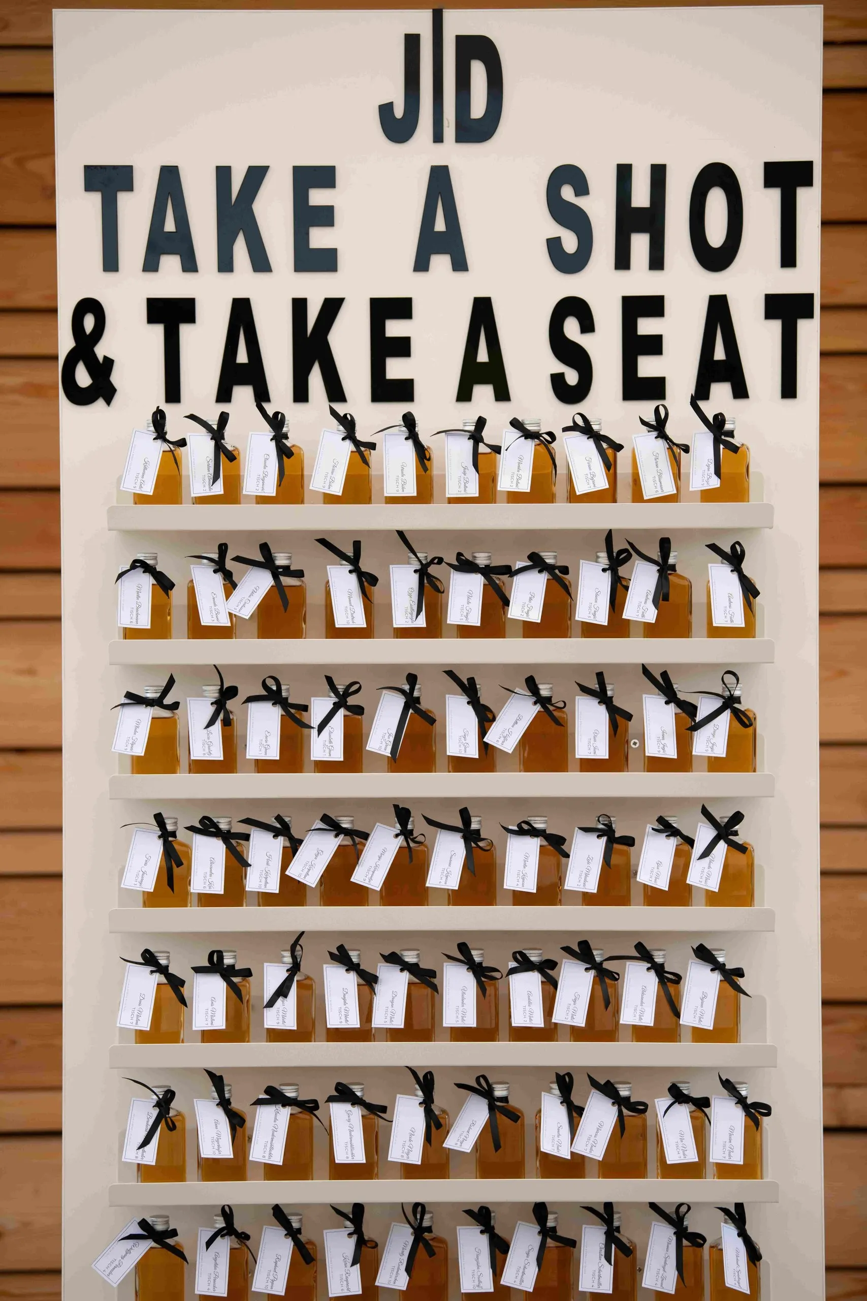 Sitzplan „Take a shot & take a seat“ mit Schnapsgläsern an einer Holzwand