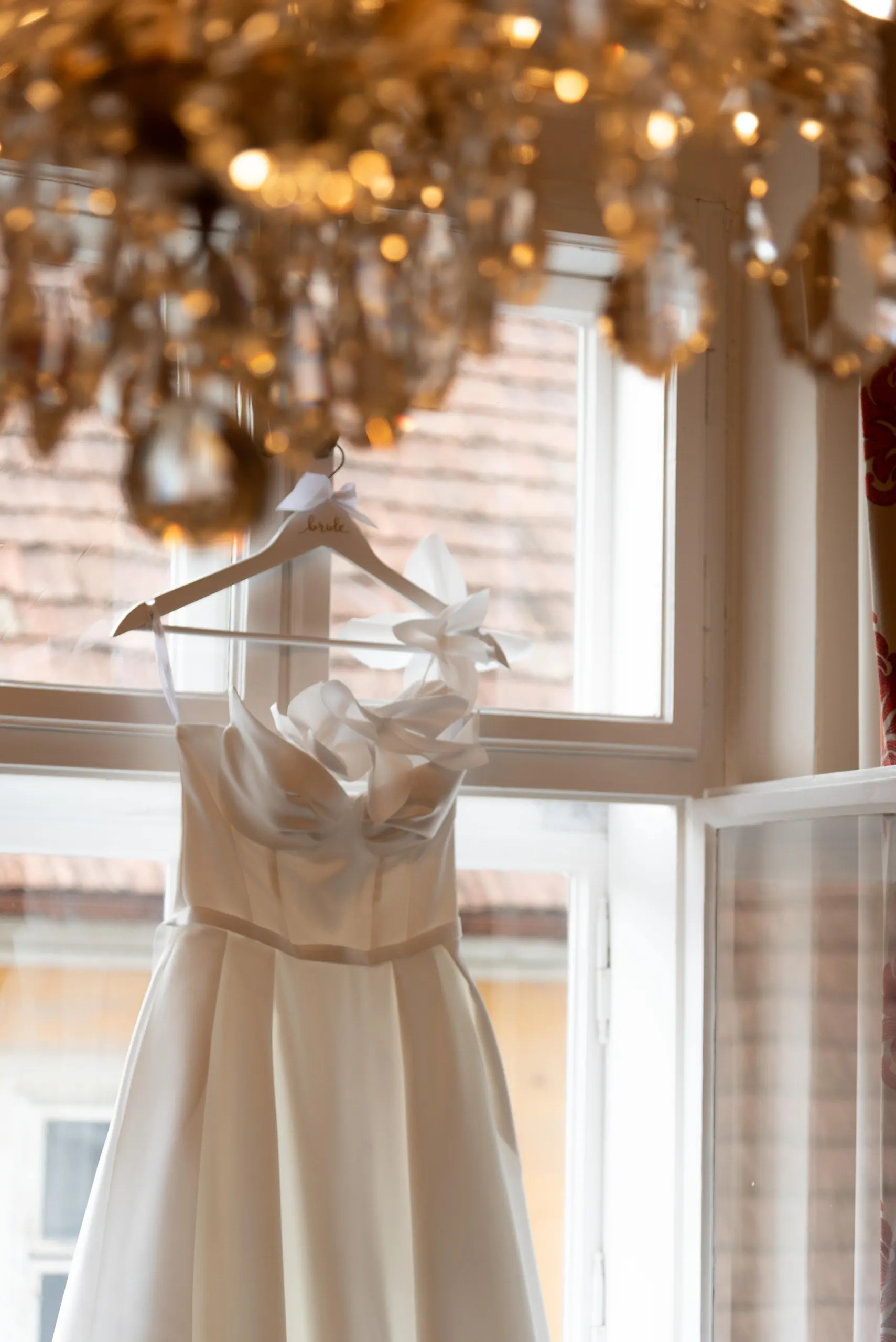 Das Brautkleid hängt am Fenster unter dem Kristallluster