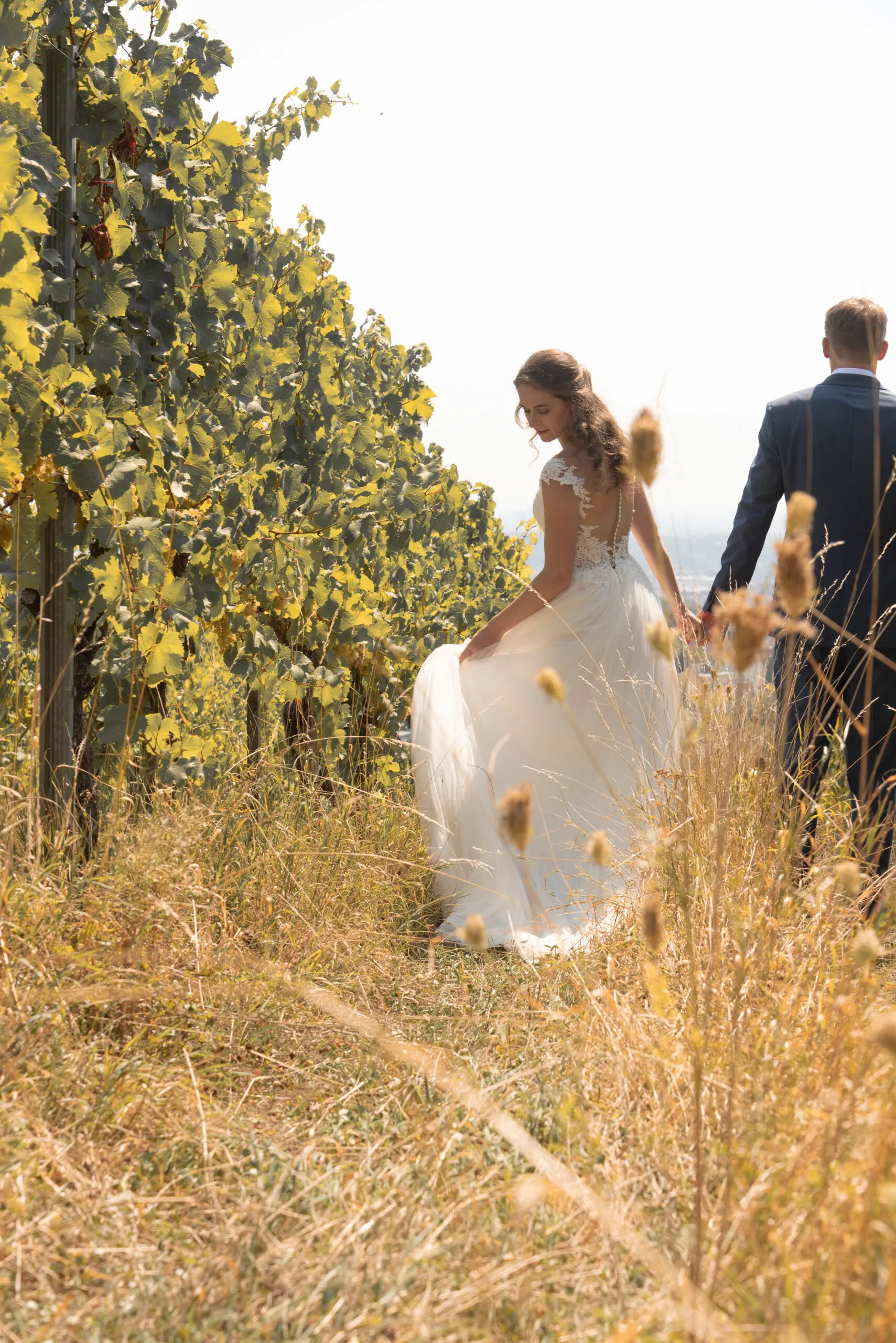 Karen rafft ihr Kleid, Hand in Hand mit Sandor im hohen Spätsommergras zwischen den Reben