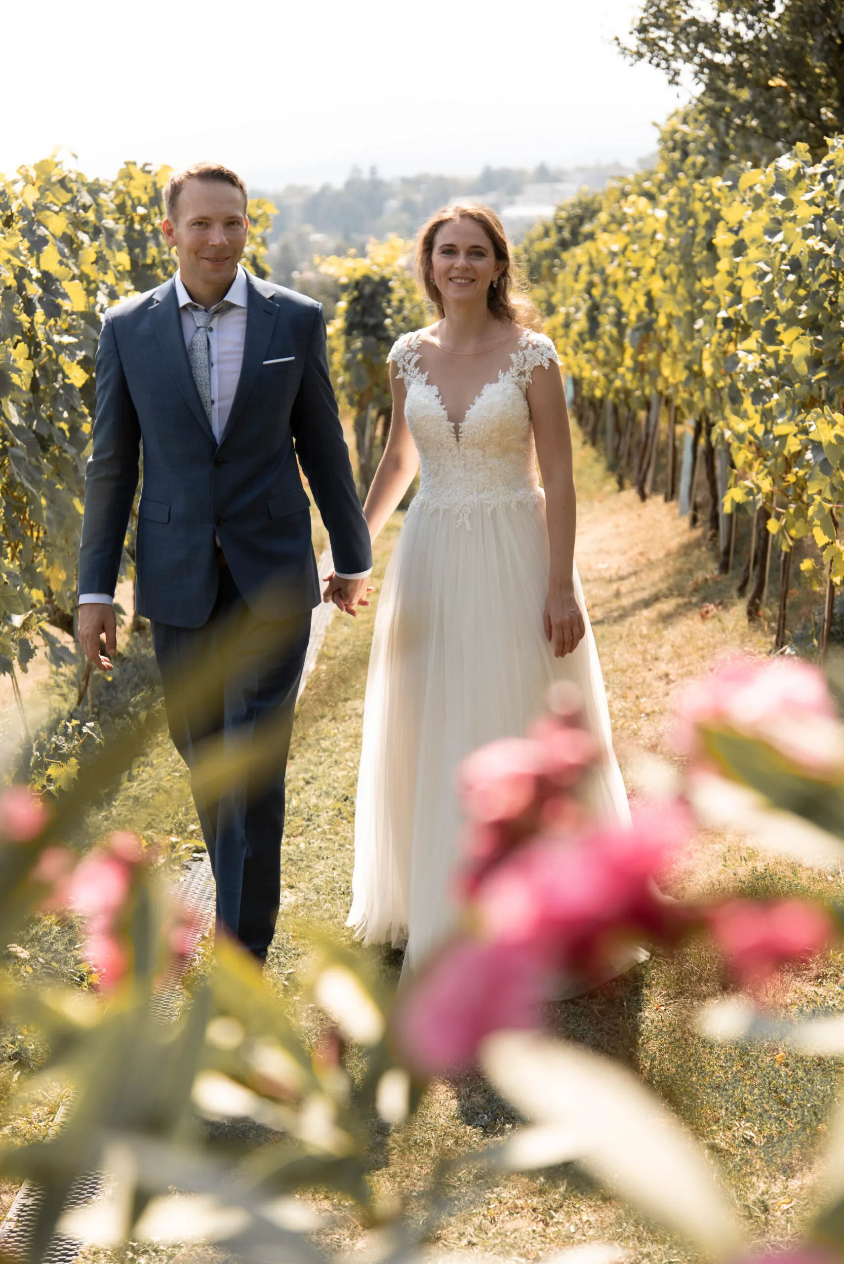 Hand in Hand kommen Karen und Sandor die Rebzeile entlang, vorn leuchten Oleanderblüten