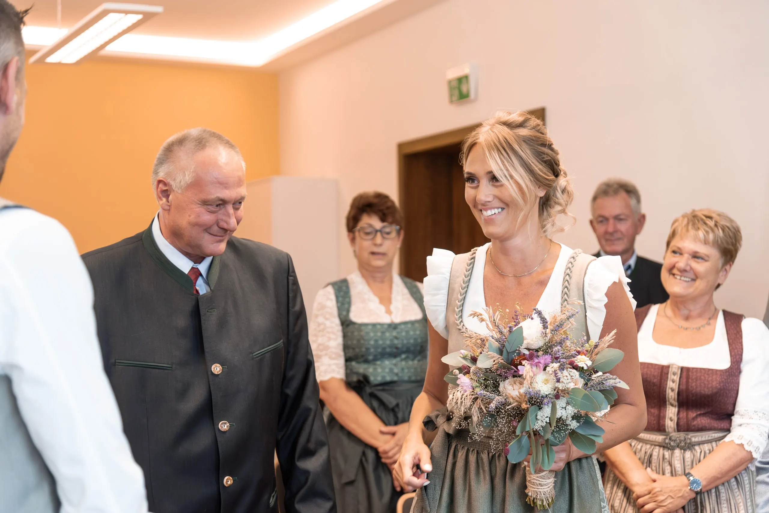 Die Braut lacht strahlend, ein älterer Mann neben ihr blickt sie liebevoll an