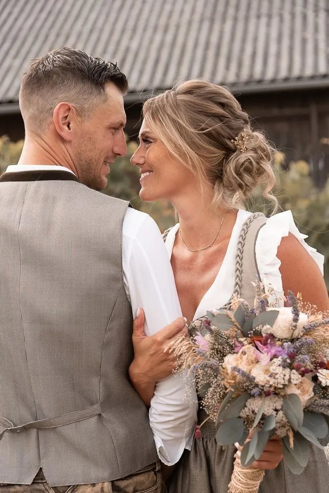 Magdalena und Thomas in Tracht Arm in Arm vor einer Scheune