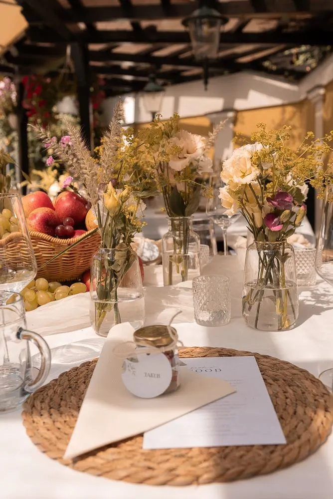 Gedeckte Tafel im Schreiberhaus: Juteplatzset, Gastgeschenk im Glas und Wildblumen