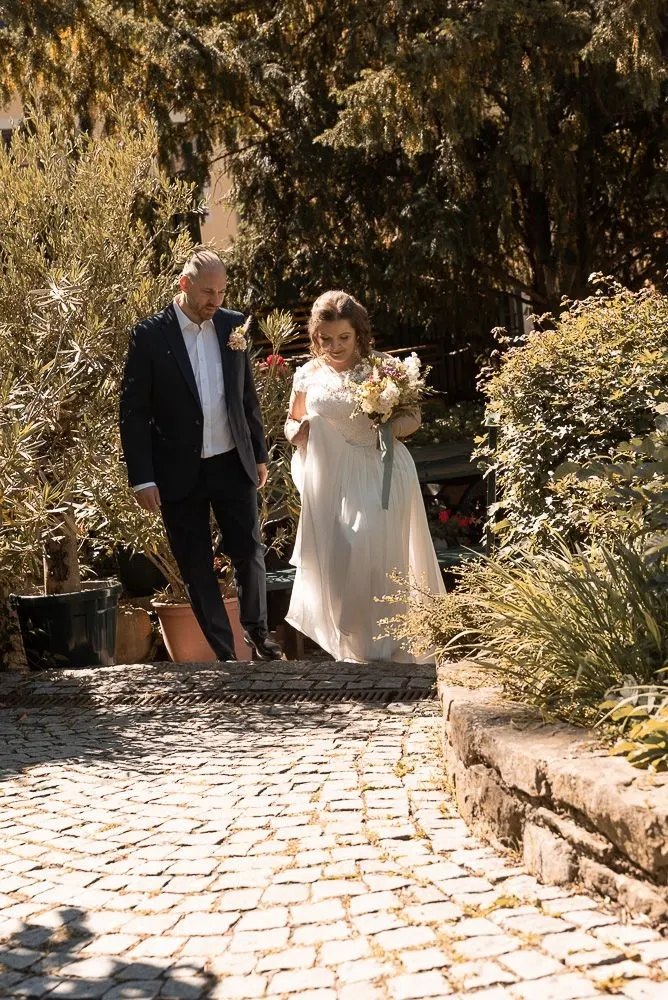Mirela und Clemens kommen Hand in Hand die Steinstufen im Garten herunter