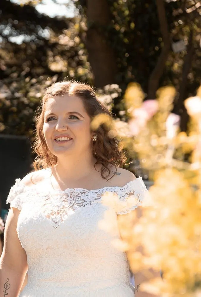 Mirela im Spitzenkleid lächelt, Wildblumen im Vordergrund