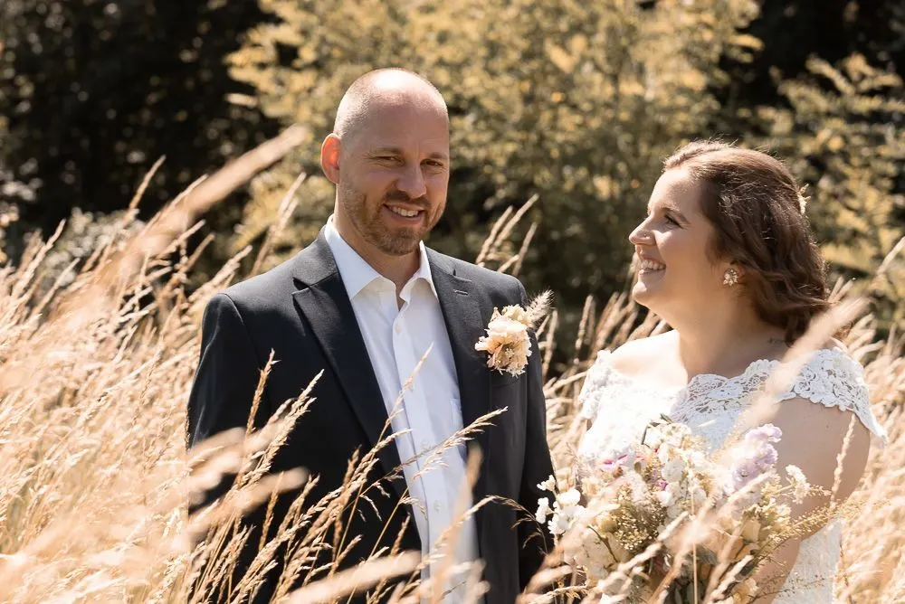 Mirela und Clemens lachen im hohen Sommergras