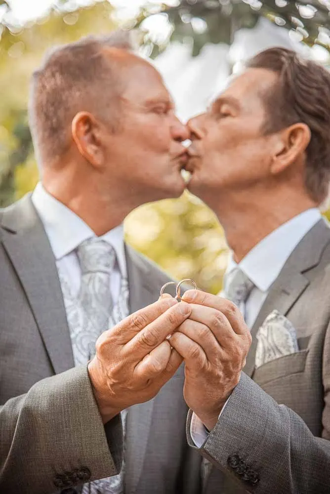 Kuss, die Hände mit den Ringen zwischen ihnen