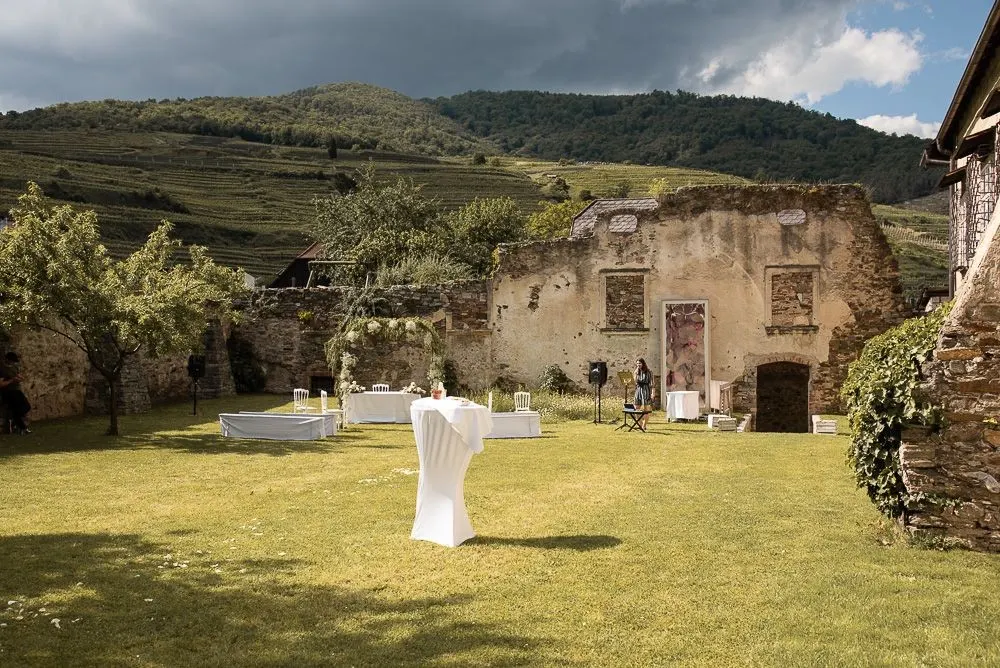 Der Schlosshof mit alten Mauern, dahinter die Weinberge